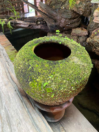 Big earthen jar, Water bowl or jar made from clay covered with moss naturally occurring in a moist and shady atmosphere put decorations in the gardenの写真素材