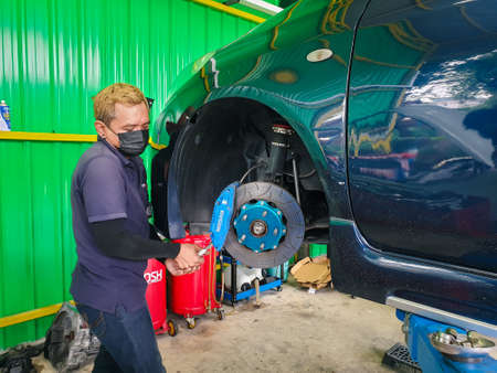 Bangkok, Thailand - August 7, 2021 : Unidentified car mechanic or serviceman disassembly and checking a disc brake and asbestos brake pads for fix and repair problem at car garage or repair shopのeditorial素材