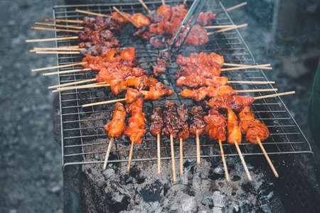Grilled chicken sauce is a Thai barbeque food by chicken and sauce cooking on charcoal with flames at Thai street food marketの写真素材