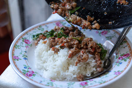 Rice topped with stir-fried pork or beef and basil for sale at Thai street food market or restaurant in Bangkok Thailandの写真素材