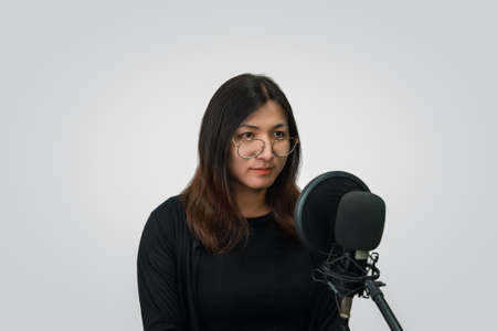 Beautiful asian woman (LGBTQ) is a singer. She enjoying sing a song or karaoke in music studio with microphone condenser and headphones for fun or voice creativeの写真素材