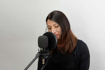 Beautiful asian woman (LGBTQ) is a singer. She enjoying sing a song or karaoke in music studio with microphone condenser and headphones for fun or voice creativeの写真素材