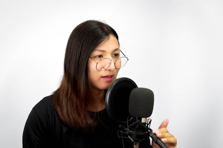 Beautiful asian woman is a singer. She enjoying sing a song or karaoke in music studio with microphone condenser and headphones for fun or voice creativeの写真素材