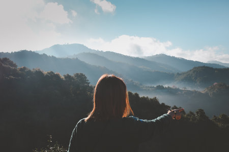 Asian pretty cute woman short jeans with hat hiking in forest on mountain with cliff with happy and freedom emotion in concept travel, active lifestyle, vacation, overcome obstacles in lifeの写真素材