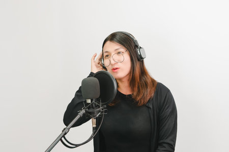 Beautiful asian woman is a singer. She enjoying sing a song or karaoke in music studio with microphone condenser and headphones for fun or voice creativeの写真素材