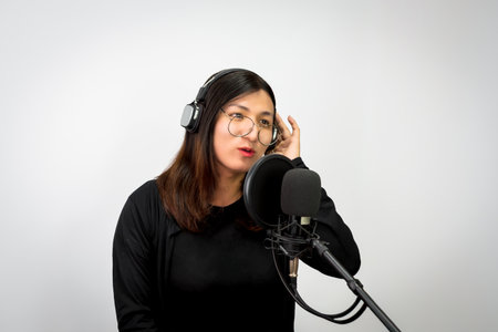 Beautiful asian woman is a singer. She enjoying sing a song or karaoke in music studio with microphone condenser and headphones for fun or voice creativeの写真素材