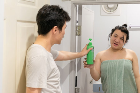 Two Thai LGBTQ friends sharing evening home routine after gardening one taking shower and another helping in cozy atmosphere showing warmth care and daily connectionの写真素材