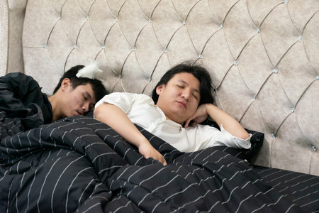 Two Thai LGBTQ friends waking up peacefully together in a cozy bedroom showing warmth love and acceptance representing calm connection trust and everyday lifestyle diversityの写真素材