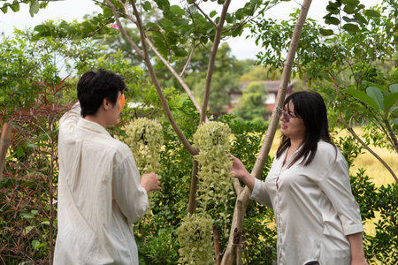 Two LGBTQ friends, one with long hair and the other with short hair, enjoy their morning in the garden. They tend to the plants and flowers while sharing a moment of connection and care for nature.の写真素材