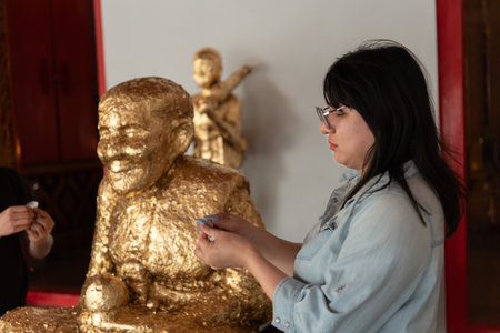 Two LGBTQ friends visiting a Thai temple for a spiritual practice. They are making merit by offering flowers and praying at the altar as part of their religious and cultural observance.の写真素材