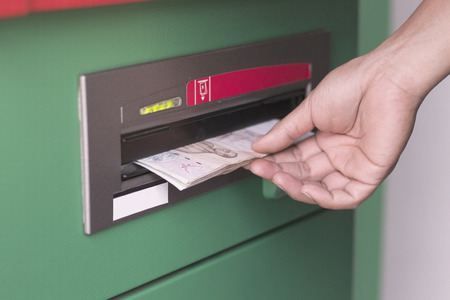 Hand taking cash out from green ATM