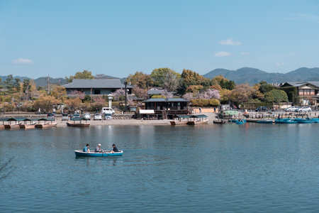 KYOTO, JAPAN - April 4, 2023: Tourists rowing boat in Katsura River in Arashiyama district with cherry blossom in spring timeのeditorial素材