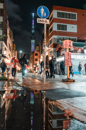 TOKYO, JAPAN - APRIL 7, 2023: People walking around Senso-ji temple in Asakusa area in the evening with rain drizzleのeditorial素材