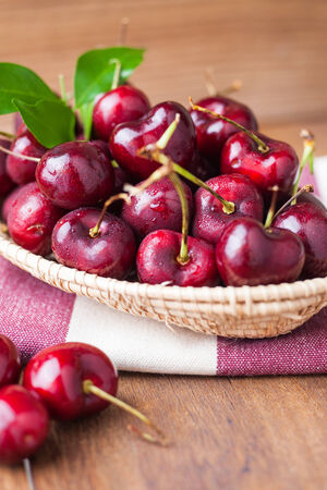 Many fresh cherries in bamboo basket on the fabricの写真素材