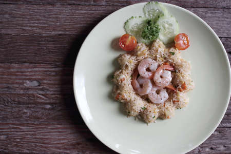 Shrimp fried rice dish in white on a wooden floor.の写真素材
