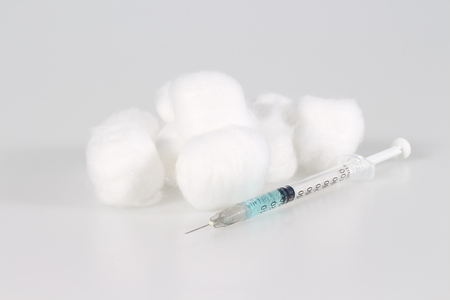 Medical syringe with needle and cotton ball on the white backgroundの写真素材