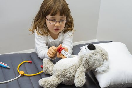 Child girl playing doctor with a toy. Rescuing of endangered animals.  Profession and care concept. Clear neutral background.の写真素材