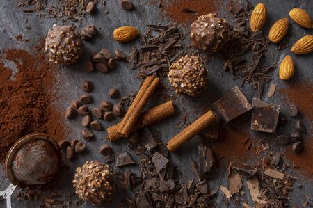 Homemade dark chocolate and almond nuts truffles surrounded by chocolate pieces and cocoa powder