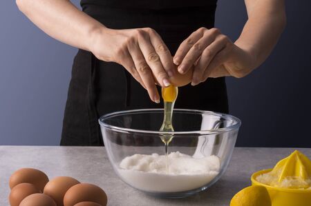 Female baker hands making dough for a homemade sweet bread. Fresh and dry ingrediends of lemons and...