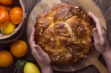 Freshly baked sweet braided bread loaf with fruit fillings and almond slices on wooden background....