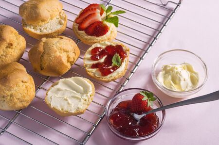 Tasty breakfast of scones with clotted cream and strawberry jam on pink background, top viewの写真素材