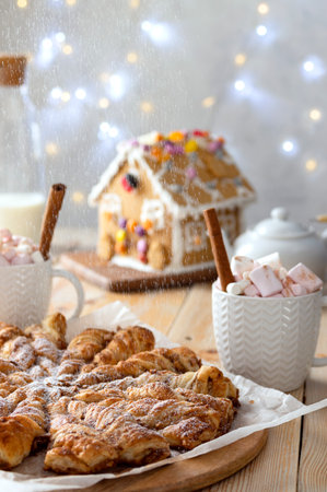 Cinnamon twists and hot chocolate for Christmas afternoon breakfast treat on illuminated with lights backgroundの写真素材