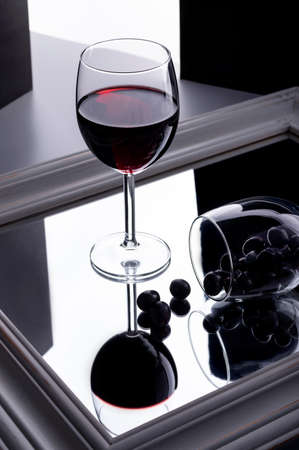 A glass of wine stands on a mirror on split black and white background. Minimal compositionの写真素材