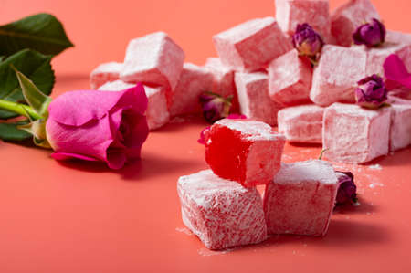 Levitating rose flavored pink Turkish delight with flower petals and dry rose buds on pink...