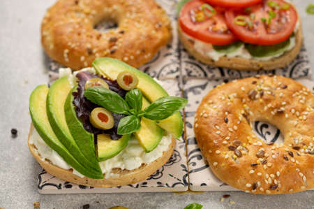 Fresh healthy sandwiches with seeded bagel, slad  and cotage cheese on grey