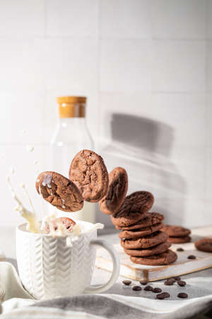 Fresh chocolate ship cookies making splash in a cup of milk