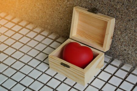 The heart is placed in an open wooden box, on white mosaic floor background, object, copy spaceの写真素材