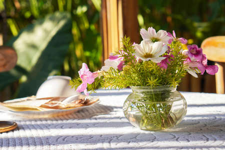 front view pink and white flowers and green leaf in glass vase on white fabric on table, blur nature background, nature, decor, object, copy spaceの写真素材