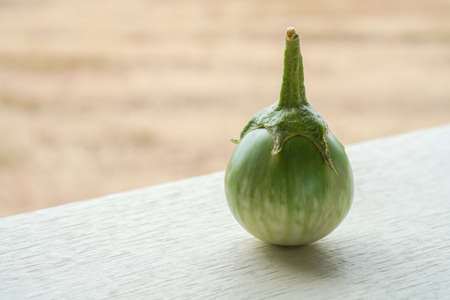 one solanum melongena vegetable on white dish on white wooden floor background, blur brown nature background, vegetable, health, copy spaceの写真素材