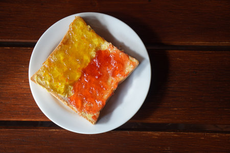 Toast Strawberry Jam and Pineapple Jam put on a white plastic plate on wooden floor background, dessert, food, health, copy spaceの写真素材