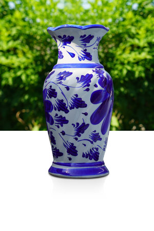 antique blue and white ceramic vase on white floor, blur green trees background, object, decor, vintage, fashion, nature, copy spaceの写真素材