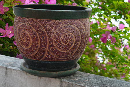 antique red and green clay pot on green clay tray put on the cement wall, on bougainvillea pink trees background, object, decor, modern, gift, copy spaceの写真素材