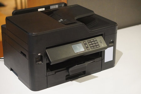 old black plastic printer and white paper on white desk background, technology, object, office,...