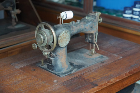 side view antique and dirty black and brown sewing machine on wooden sewing machine table, spool of white thread, object, technology, work, decor, copy spaceの写真素材