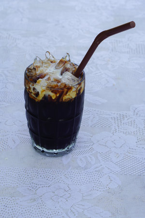 Top view Thai Coffee and milk mixed is in a clear glass, brown tube Placed on a white fabric...
