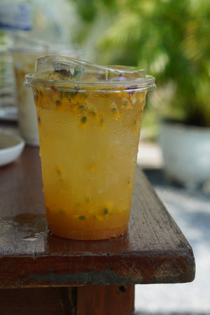 Passion Fruit Soda in a clear plastic glass. decorated with flowers and leaves on wooden table, blur nature background, fruit, nature, drink, fresh, copy spaceの写真素材