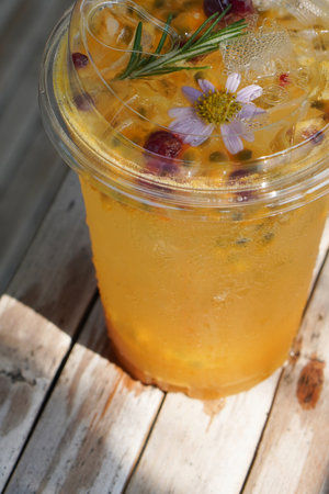 top view closeup Passion Fruit Soda in a clear plastic glass. decorated with yellow pollen and violet flowers and green leaves on old bamboo floor background, fruit, nature, drink, fresh, copy spaceの写真素材
