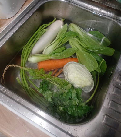 Top view Clean and soak vegetables,  coriander, carrots, Chinese kale, green beans, and cabbage in the sink on wooden background, protect, clean, fresh, copy spaceの写真素材