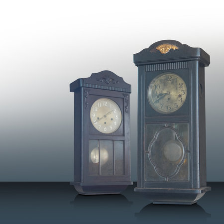 Antique and old two brown and black color wall clocks on black floor, gradient white and grey...