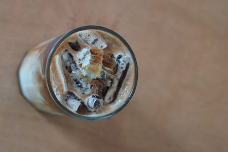 top view focus black and brown coffee, honey, and a toasted nest and ice in the glass on brown floor...
