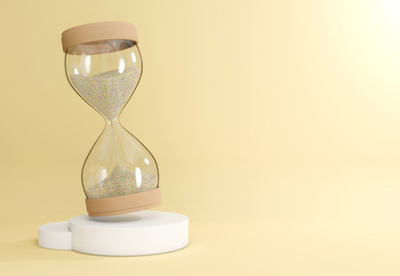 A clear glass hourglass filled with light-colored sand is placed on a white cylindrical base. Simple...
