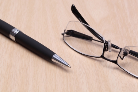 pen and glasses on wood tableの写真素材