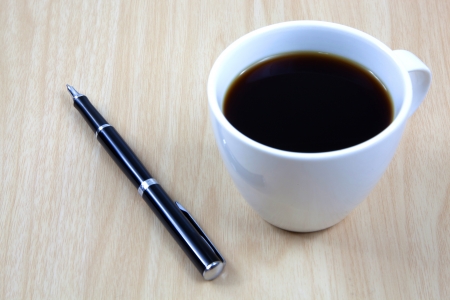Cup of coffee on a wooden table with penの写真素材