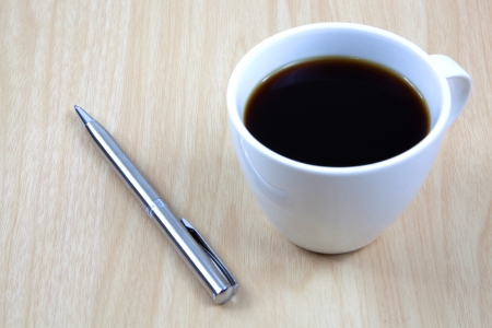 Cup of coffee on a wooden table with penの写真素材