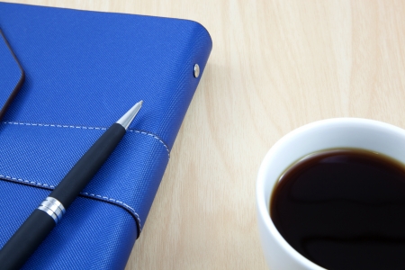 Cup of coffee on a wooden table with book and penの写真素材