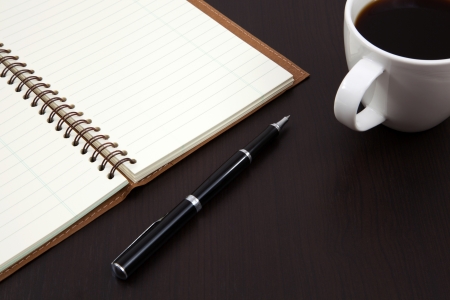 Cup of coffee on a wooden table with book and penの写真素材